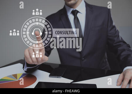 Businessman pressing button on touch screen interface and select Consulting. Business, internet, technology concept. Stock Photo