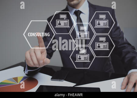 Businessman pressing button on touch screen interface and select Consulting. Business, internet, technology concept. Stock Photo