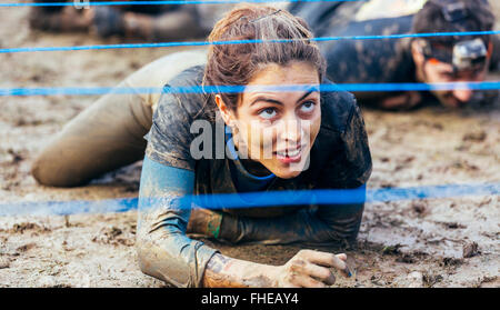 Participants in extreme obstacle race crawling under electric wire Stock Photo