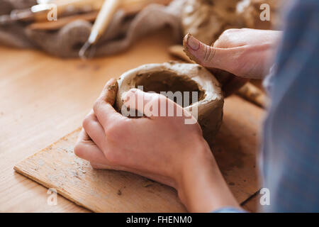 Closeup of woman hands making pot using clay in pottery studio Stock Photo
