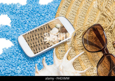 Straw hat, sunglasses and a seashell are lying on a little blue stones forming a wave isolated on the white. Stock Photo