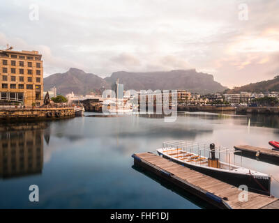 Waterfront in Cape Town, South Africa, overlooked by Table Mountain at sunset.