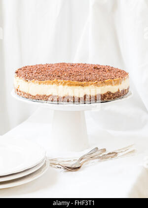 Whole vegan millet cheesecake with date caramel on a cleat background. Stock Photo