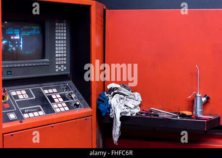 close-up of the control panel of an industrial machinery, painted in red, with buttons and knobs and a screen Stock Photo