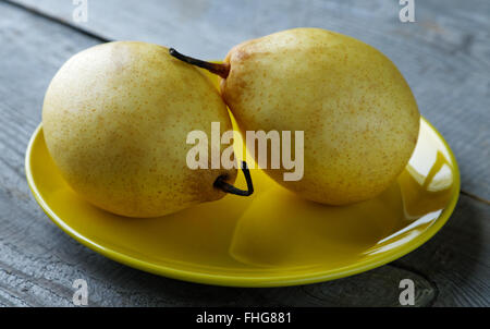 Two yellow pears on the plate on a rustic table Stock Photo