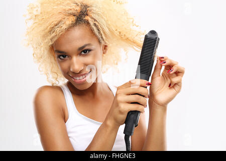 Hair straightener. Styling using the straightener. Young girl straightens her hair with a hair straightener Stock Photo