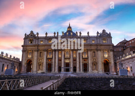 Front view of St Peter's Basilica in Vatican with people around, on cloudy blue sky backgroundat sunset time. Stock Photo
