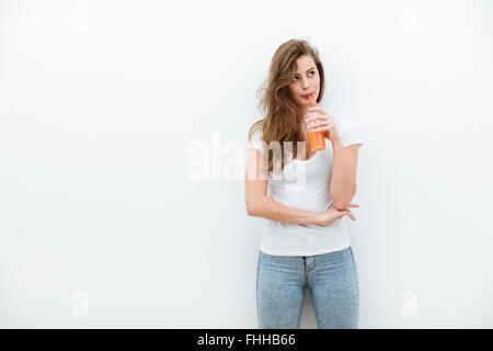 young beautiful woman drinking orange or carrot juice in hand, on white background Stock Photo