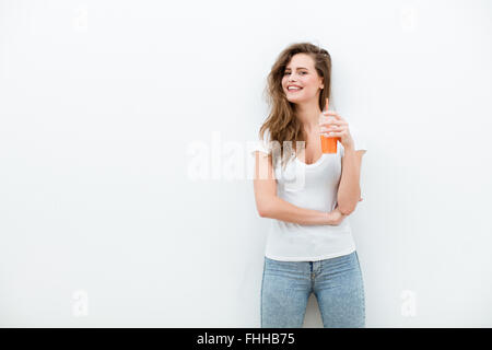 young beautiful woman with glass of orange or carrot juice in hand, on white background Stock Photo
