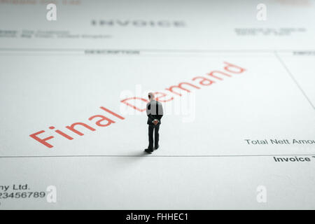 Miniature business man gloomily pondering an overdue final demand invoice a finance or debt concept Stock Photo