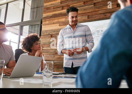Portrait of young man with colleagues having meeting in conference room. Diverse group of young designers brainstorming in board Stock Photo