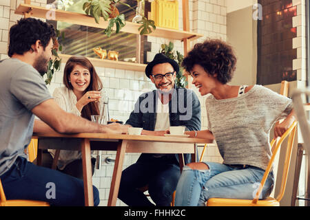 Portrait of cheerful young friends having fun while talking in a cafe. Group of young people meeting in a cafe. Stock Photo