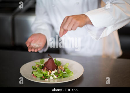 Chef seasoning salad on counter Stock Photo