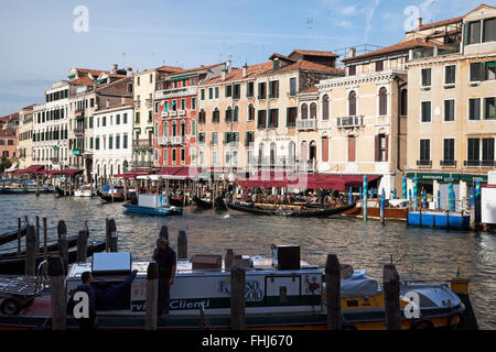 Sunlit buildings and gondolas along the Grand Canal, Venice with service boats in the foreground Stock Photo