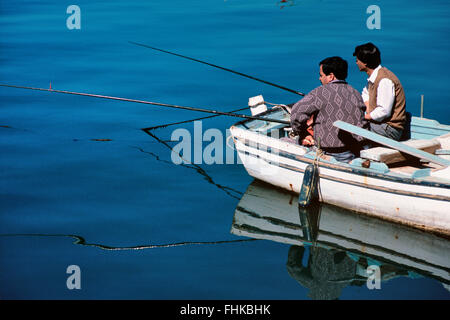 Two Turkish Fishermen Fishing from Rowing Boat in Bodrum Harbor, Bodrum, Turkey Stock Photo