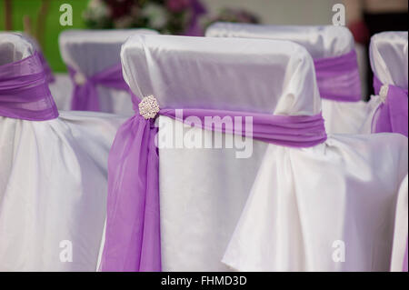 beautiful white wedding chairs decorated with purple bows Stock Photo