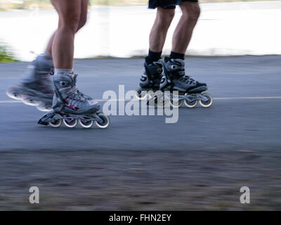 Male and female inline skaters with blurred background and foreground Stock Photo