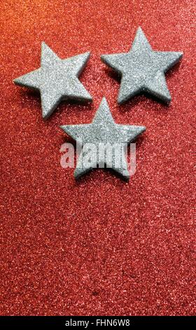 three large silver stars on bright red glittery background Stock Photo