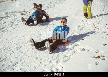Italy, Val Venosta, Slingia, family sleighing down a snowy hill