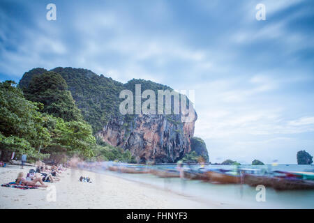 A long exposure image of long boats and tourist on Phra Nang beach in Railay, Krabi Province, Thailand Stock Photo