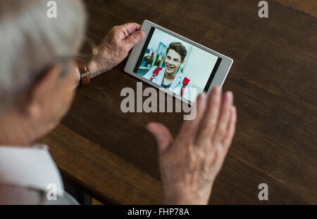 Senior man using mini tablet for skyping with his grandson Stock Photo