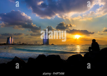 Dubai, United Arab Emirates - Dec 2, 2014 : Man enjoying the illuminated Burj Al Arab,a luxury 7 stars hotel, and Jumeirah Beach Stock Photo