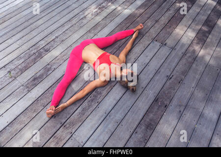 Woman in yoga straddle position on deck Stock Photo
