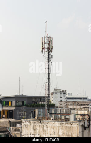 Telecommunication tower with multiple antennas and data transmitters with beautiful city in the background and wide mountain are Stock Photo