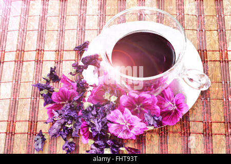 Cup with infusion of mauve flowers. Stock Photo