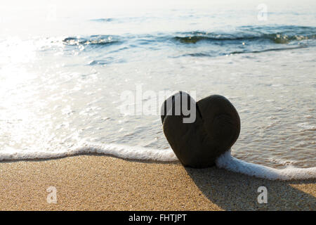 Heart shaped rock washed by the sea on a sandy beach. Stock Photo