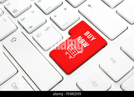 Shop online buy now business concept, Red shopping cart button or key on white keyboard photography. Stock Photo