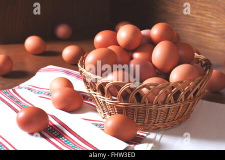 Fresh chicken eggs in a wooden basket on a towel with ornament Stock Photo