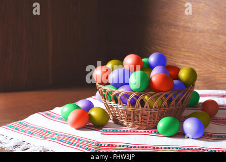 A basket of beautiful and colourful vivid easter eggs in a woven basket. Easter stock image Stock Photo