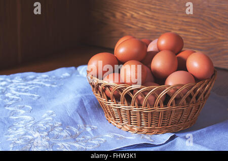 Fresh chicken eggs in a wooden basket on a blue linnen blanket. Food stock image Stock Photo