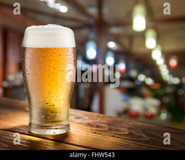 Glass of light beer on the glass bar counter. Stock Photo