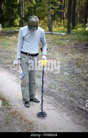 Man searching coins on an old road with metal detector Stock Photo