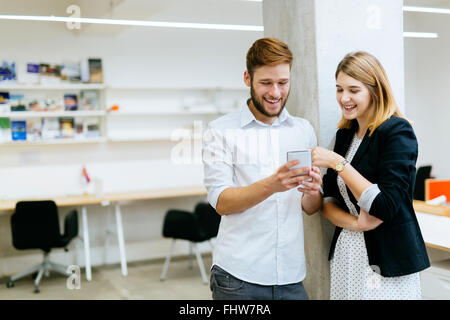 Businessman businesswoman smiling while looking the phone in office Stock Photo