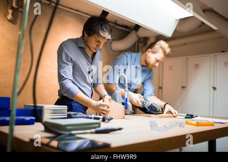 Two creative designers working in workshop with precision tools manufacturing a new product Stock Photo
