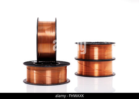 Copper welding wire wounded on the spools isolated on white. Wire rolls. Stock Photo