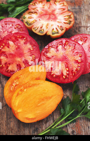Assorted Colorful Sliced Heirloom Tomatoes on rustic wood background Stock Photo