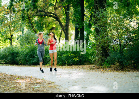 Sportive women jogging in park and listening to music through earphones