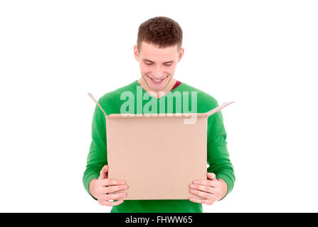 A young handsome caucasian man holding an open cardboard box in his hands and looking inside it Stock Photo