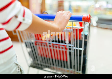 Woman shopping in supermarket and filling shopping cart Stock Photo