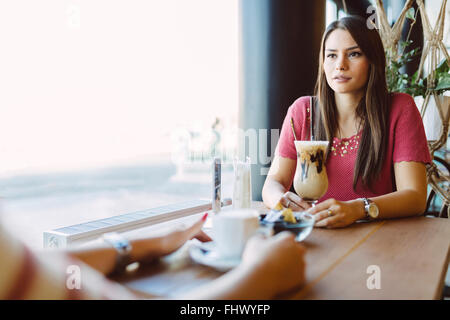 Beautiful woman talking to friend in restaurant while drinking coffee Stock Photo