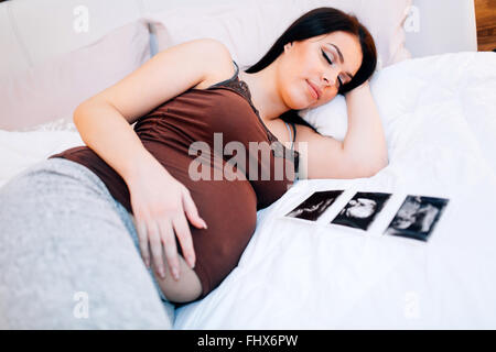 Beautiful pregnant woman resting with ultrasound scan being next to her