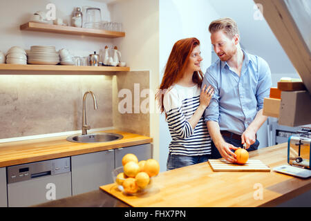 Happy couple making organic juice in kitchen and smiling Stock Photo