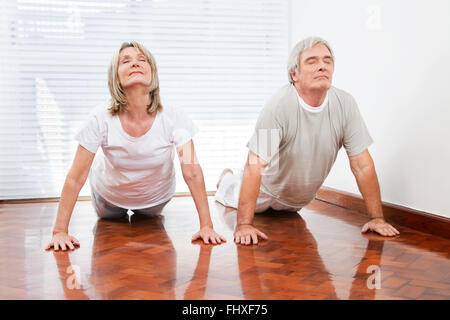Two senior people doing yoga exercise Bhujangasana in gym Stock Photo