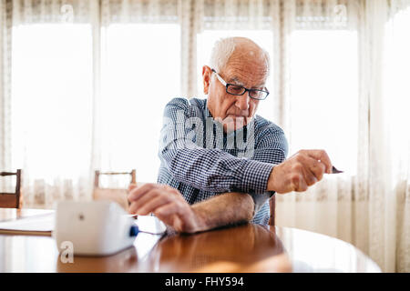 Senior man controlling his blood pressure at home Stock Photo
