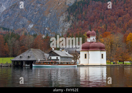 Boat with tourists in front of the Sankt Bartholomä / St. Bartholomew's Church at lake Königssee, Berchtesgaden NP, Germany Stock Photo
