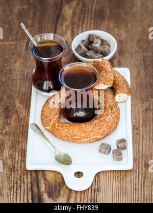 Turkish traditional black tea in a glass and turkish bagel simit on white ceramic serving board over wooden background selectiv Stock Photo